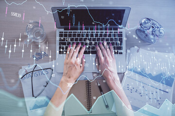 Double exposure of woman hands working on computer and forex graph hologram drawing. Top View. Financial analysis concept.