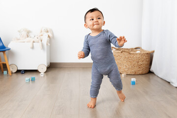 Cute toddler making first steps in playroom
