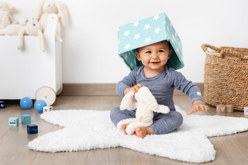 Happy baby in playroom with basket on head
