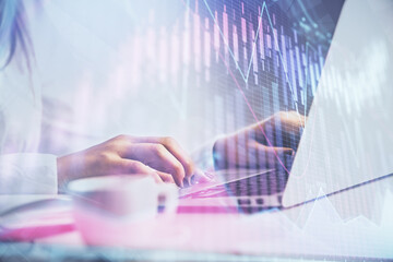 Double exposure of woman hands working on computer and forex graph hologram drawing. Financial analysis concept.