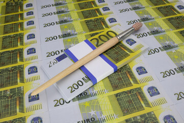 An artistic brush lies on a wad of money, on a heap of 200 Euro bills