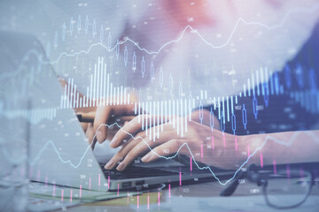 Multi exposure of woman hands typing on computer and financial graph hologram drawing. Stock market...