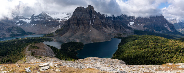 A panorama with clouds above snowy mountains and lakes in the backcountry of British Columbia, Canada.
