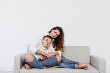 Fototapeta na wymiar Mom and son sit on the sofa at home in a white room