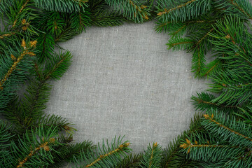Fototapeta na wymiar Green branches of a Christmas tree on a fabric background. Christmas theme, frame for text. Twigs of a Christmas tree top view. Minimalis without decorations.