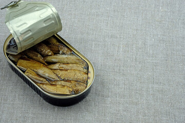 Canned sprats on a gray fabric background top view. Sprats in a tin can with a copy space. Canned...