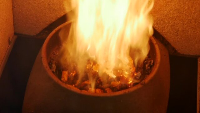 Slow motion of Heated pellet stove cylinder filled with wooden biofuel throwing out fire flames with powerful burning. Pellet granules burning slowly and going out, flames flying in the pellet stove