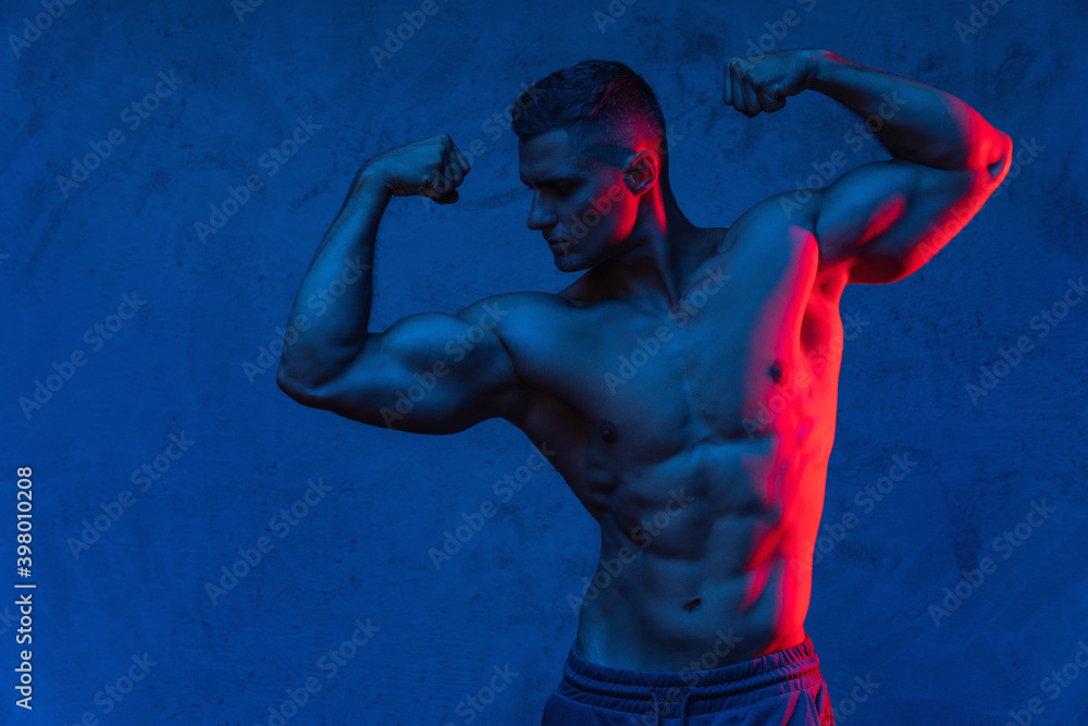 Wall mural muscular man posing in the colorful light