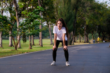 Young beautiful sport woman tired and exhausted breathing. Sportswoman taking break from running workout at a park in morning.