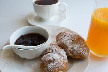 Fresh croissant and strawberry jam on a white plate.