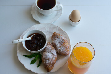 Fresh croissant and strawberry jam on a white plate.