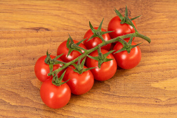A bunch of red cherry tomatoes isolated on a brown wooden table