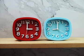 Clocks with time zone of different country on wooden shelves and marble background