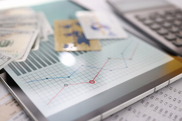 On table is tablet with commercial indicators of bank cards and banknotes