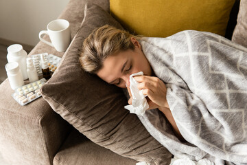 Woman with a runny nose symptom lying under the blanket at home