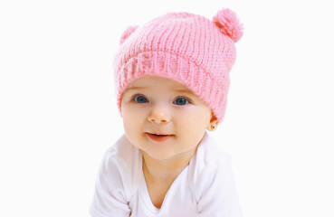 Portrait close up of sweet baby wearing a knitted pink hat over a white background