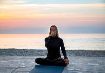 Fototapeta na wymiar middle-aged woman doing yoga breathing gymnastics at sunrise on the b