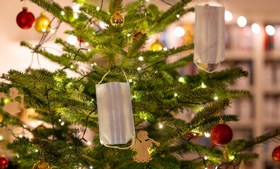 Face masks hanging in a beautiful Christmas tree. Symbol for Christmas celebrations during the...