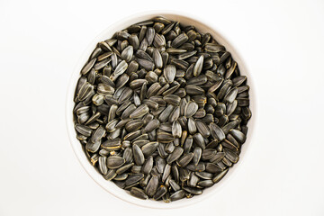 Sunflower seeds in the bowl on the white background, large group of seeds, high angle view