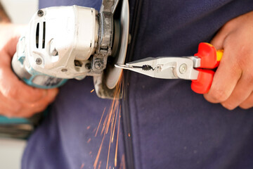 Handwerkerhand, Schlosser mit Zange schleift mit einem Flex metal. Fliehende funken mit hoch...