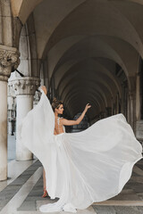 Young woman wearing beautiful white dress in a archway near the Piazza San Marco