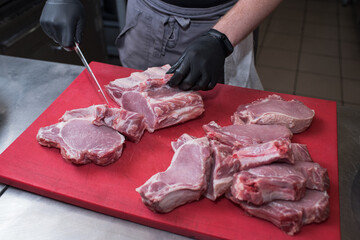 Cutting pork meat. Chef working in the kitchen in a pub