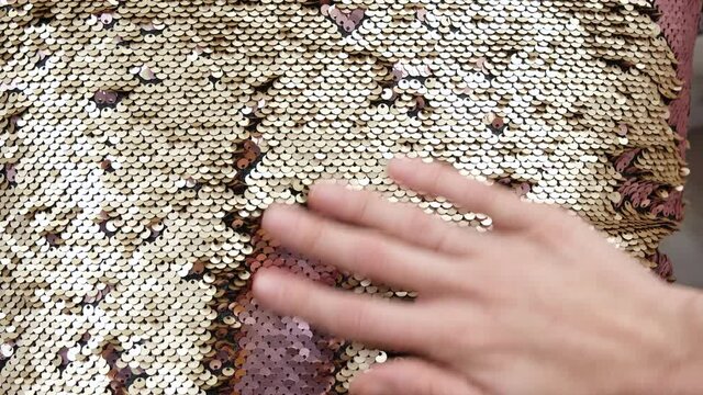 The hand stroking round golden sequins close up Hand Touches a shiny textured Gold sequins pillow surface Hypnotic meditative Texture scales of round sequins with transition