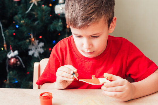 Cute 7 years old child boy paints wooden dinosaur toy for Christmas tree