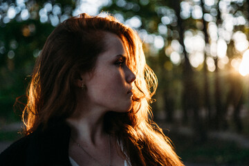 red-haired young woman in autumn in the park with beautiful healthy hair