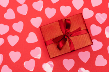 top view of pink hearts and gift box on red background