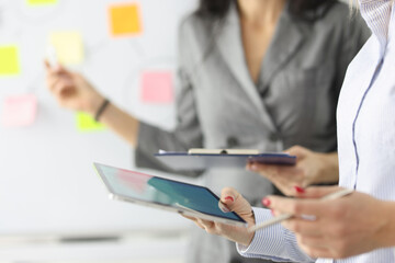 Two businesswoman are holding clipboard and tablet.