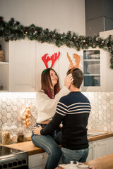 Beautiful young couple in Santa hats smiling while celebrating New Year at home