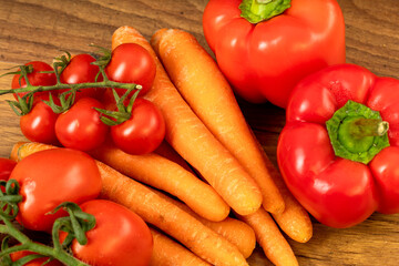 Close up of carrots cherry tomatoes and peppers on a brown wooden kitchen table