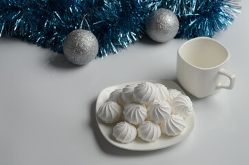 Obraz na płótnie Canvas Several meringues on a plate with a mug of tea on the background of Christmas decorations.