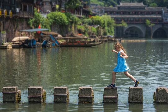 Young Caucasian girl on stepping stones in Fenghuang