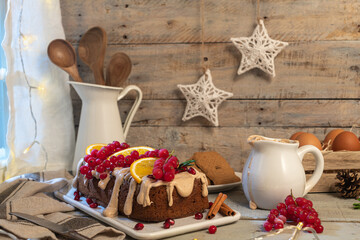 Fototapeta na wymiar Traditional christmas cinnamon cake decorated with fruits and spekulatius cookies cream on a kitchen countertop.