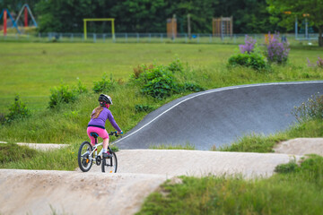 Young girl riding on her bicycle on a dirt race track