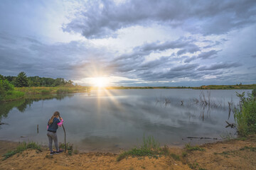 Female girl standing by a pond at sunrise