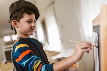 Cute little boy painting a picture in home studio