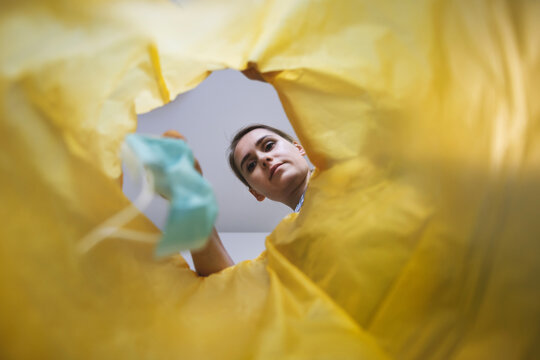 Woman Throwing Medical Face Mask In Trash Bin