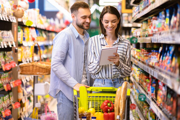 Young couple with shopping list in supermarket