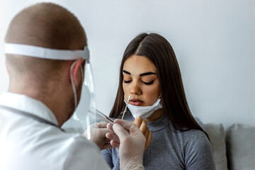 Medic taking sample from patients mouth for coronavirus testing. Photo of Caucasian young woman...