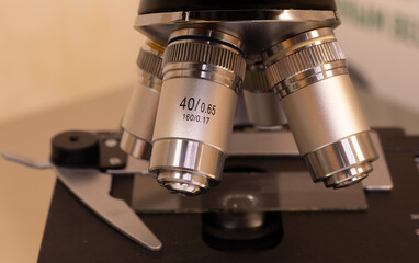 Close-up photography from the side of a microscope lens with different resolutions. At the bottom of the photo, you can see the slide table, holders, and glass.
