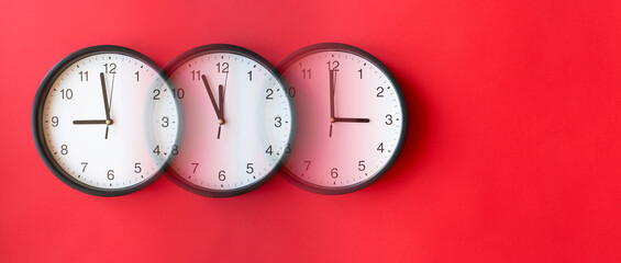 Round wall clocks on red surface showing 9, 12, 3, layout, top view, place for text.