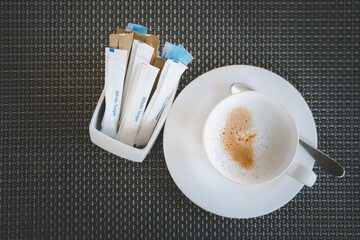 cappuccino hot coffee and sachet of sugar on dark plastic mat , diet concept , loss weight  , top...