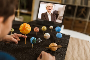 Fototapeta premium Kid presenting his science home project - the planets of our solar system. Distance learning online education.