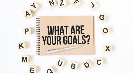 Text What Are Your Goals on the craft colored notepad with block wood cubes on the white background