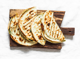 Spinach and mozzarella cheese vegetarian grilled quesadilla on a light background, top view