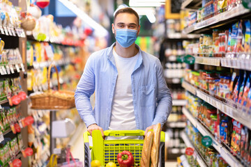Young man in mask with the cart shopping in supermarket