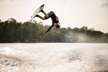 extreme guy having fun on wakeboard jumps over splashing river water